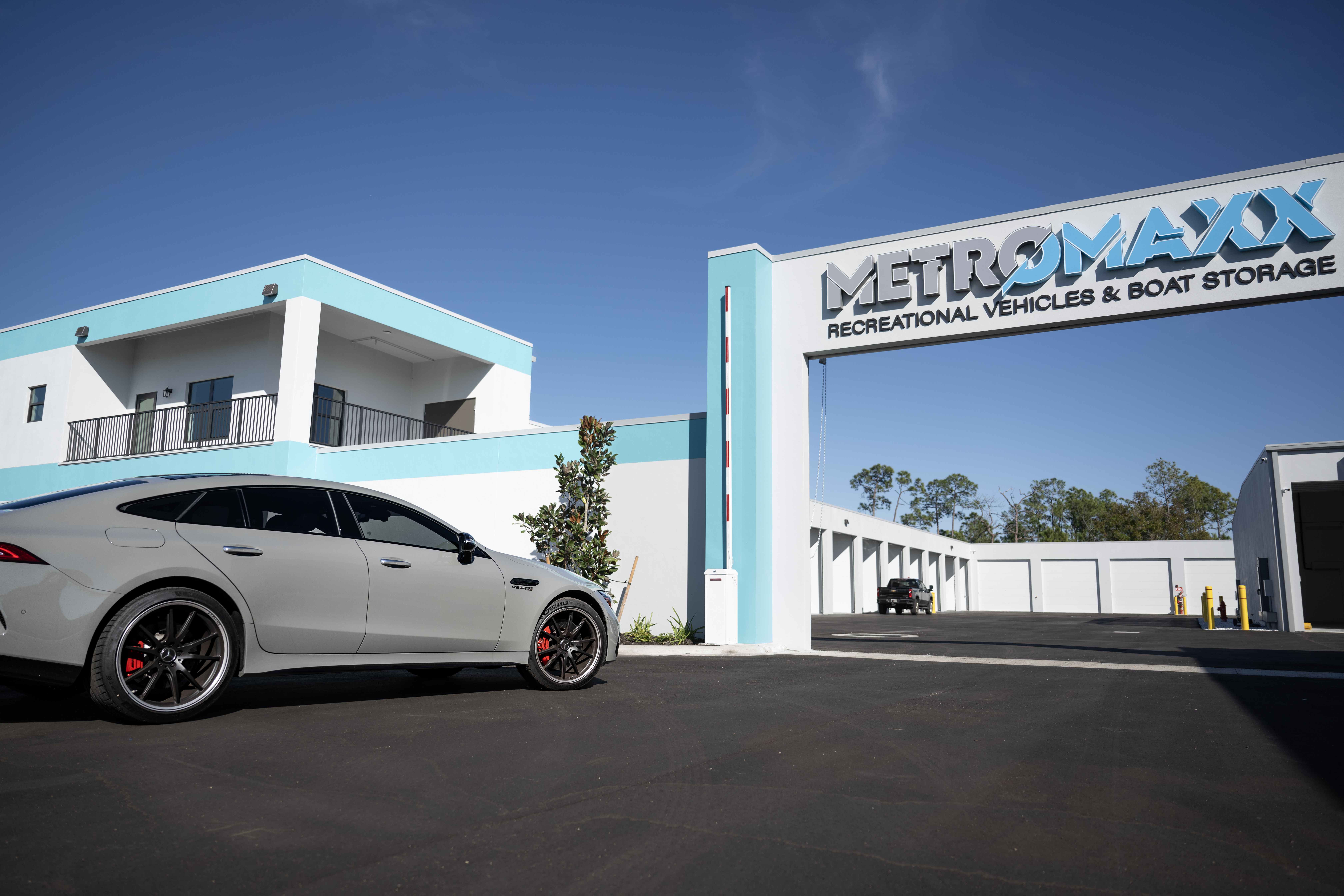 Modern main entry gate and exterior view of MetroMaxx RV & Boat Storage with private climate-controlled storage buildings and a luxury vehicle in Fort Myers, Florida